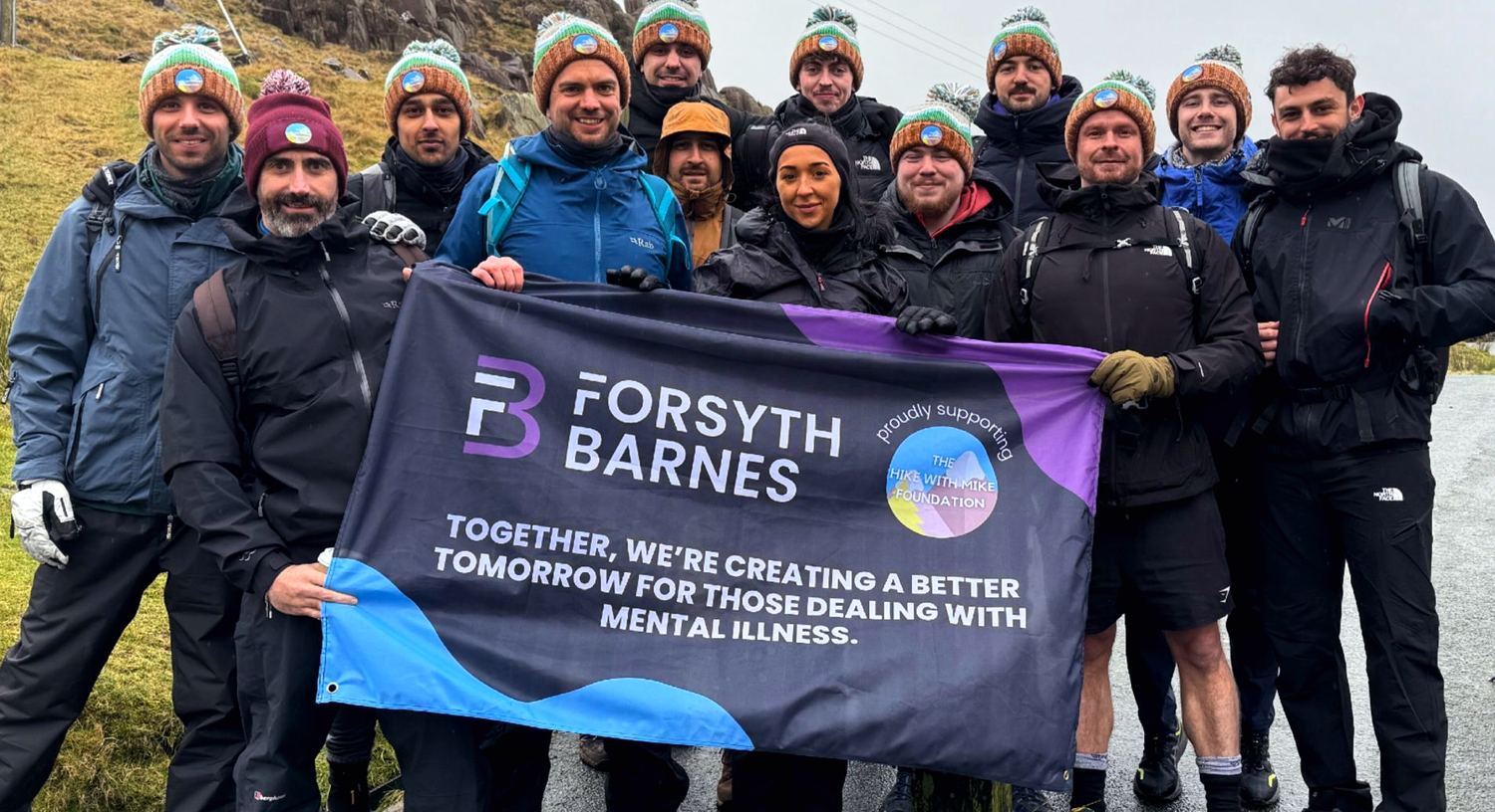 The Forsyth Barnes team on a charity hike, holding a banner supporting the Hike With Mike Foundation